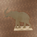 White elephant cutout on a white platform against a patterned wall.