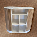 White and wood-patterned shelf unit against a patterned wall.