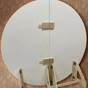 Round white board with wooden stand on a patterned background