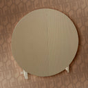 Round mirror with a beige frame on a patterned wall