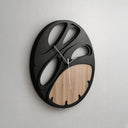 Modern wall clock with black and wood design on a light gray background
