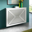 Decorative white radiator cover against a teal wall with a vase of flowers on top.